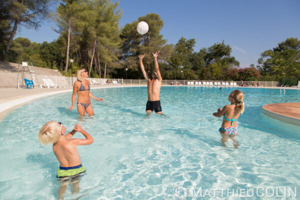 Vacances pour tous, famille avec deux enfants à la piscine, jeu de ballon